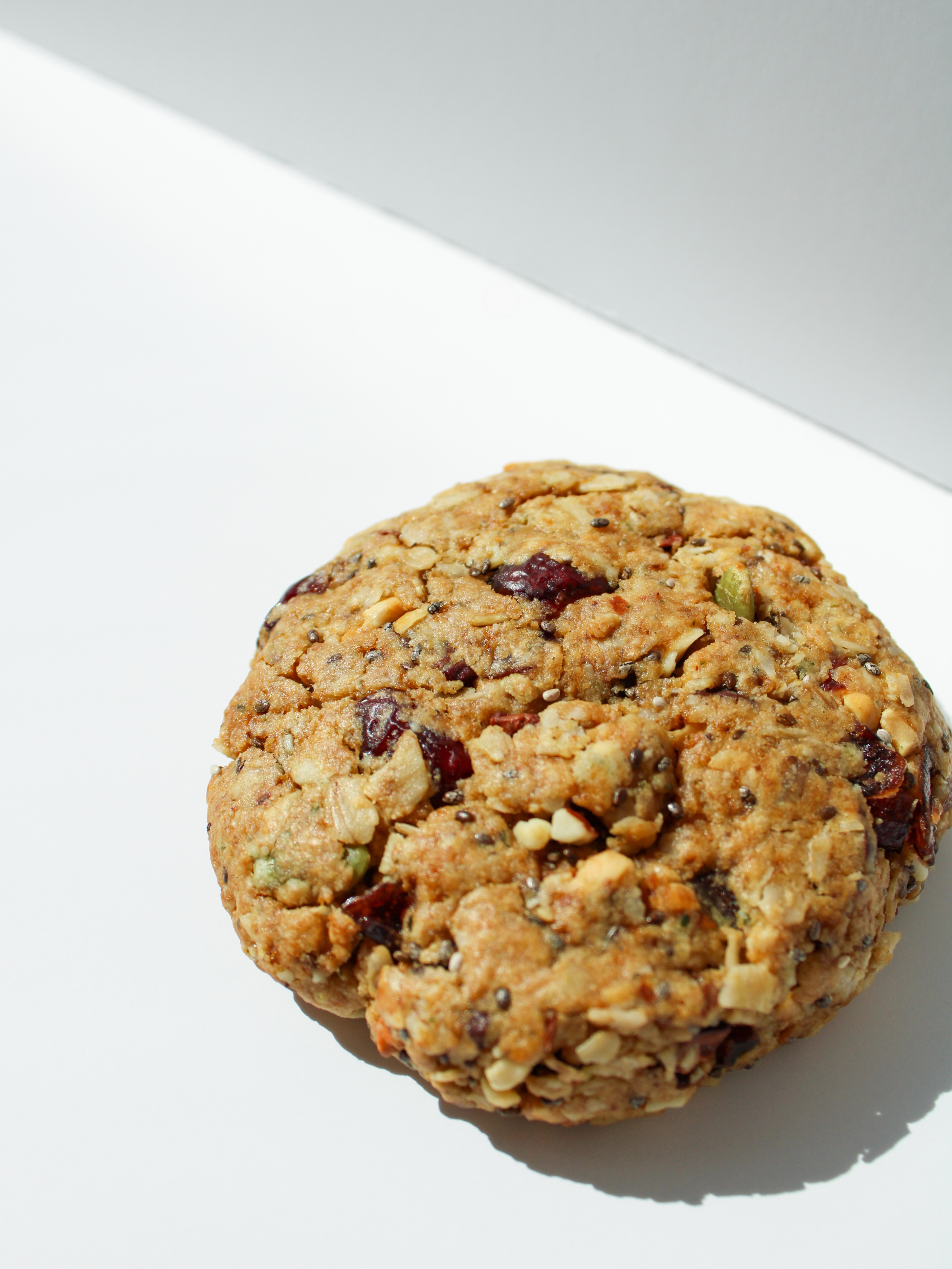 whole grain, nut, berry, and seeds power protein cookie against a white backdrop