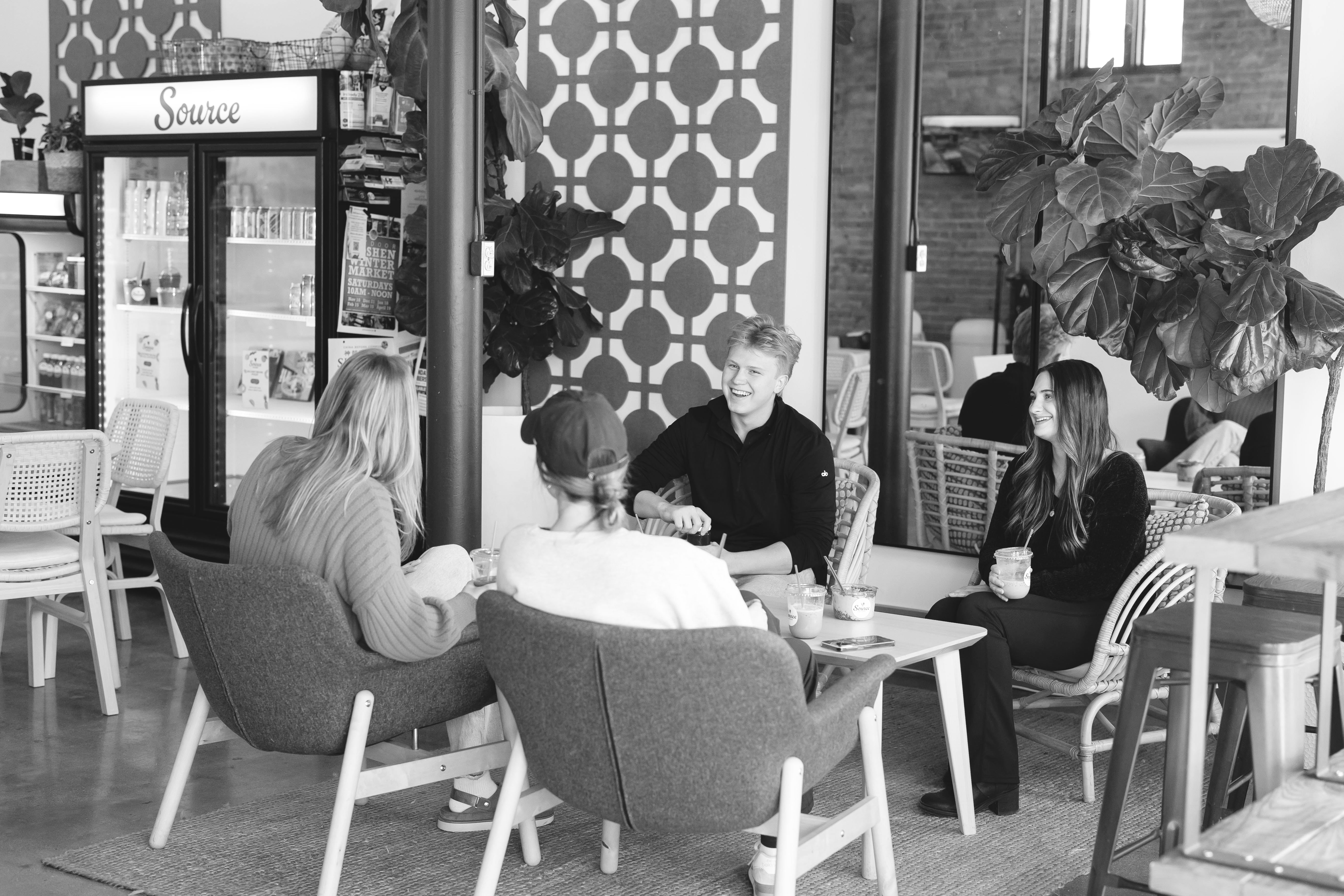four people sitting in a café conversing and laughing with each other