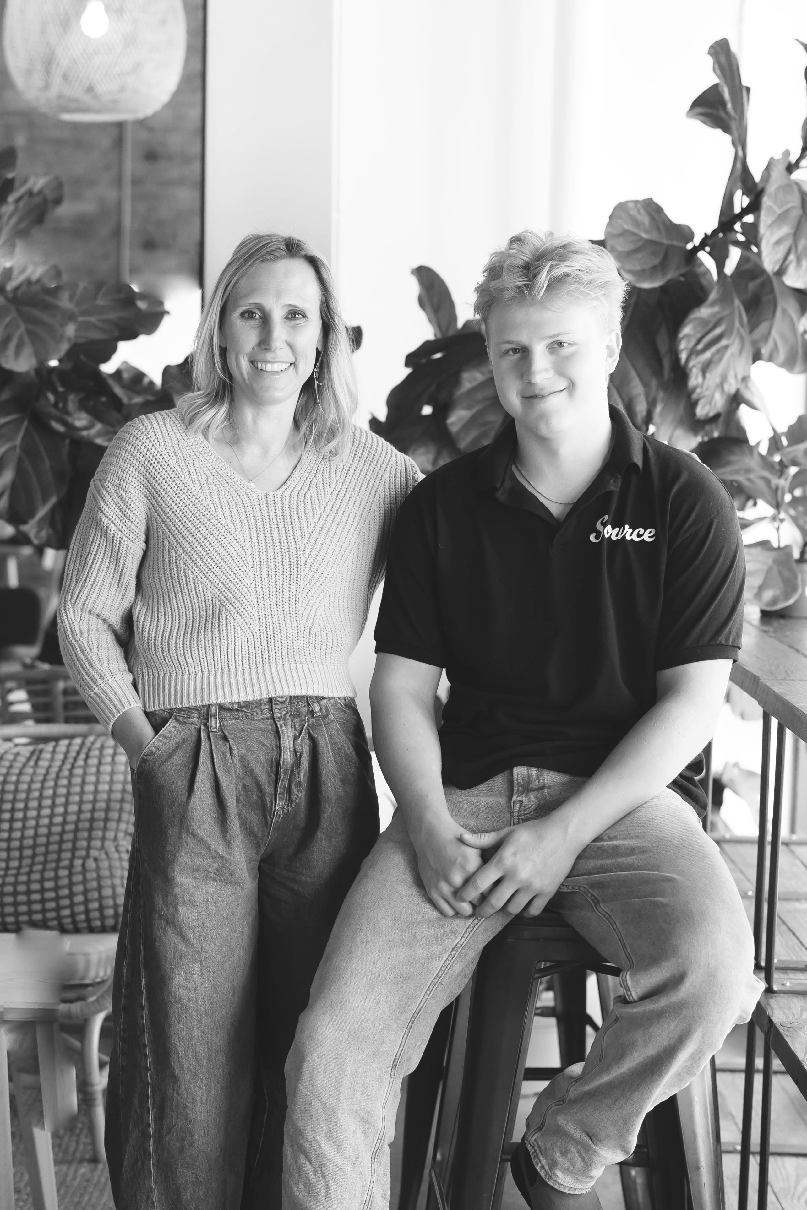 a woman and her son standing together in a café posing for a staged shot
