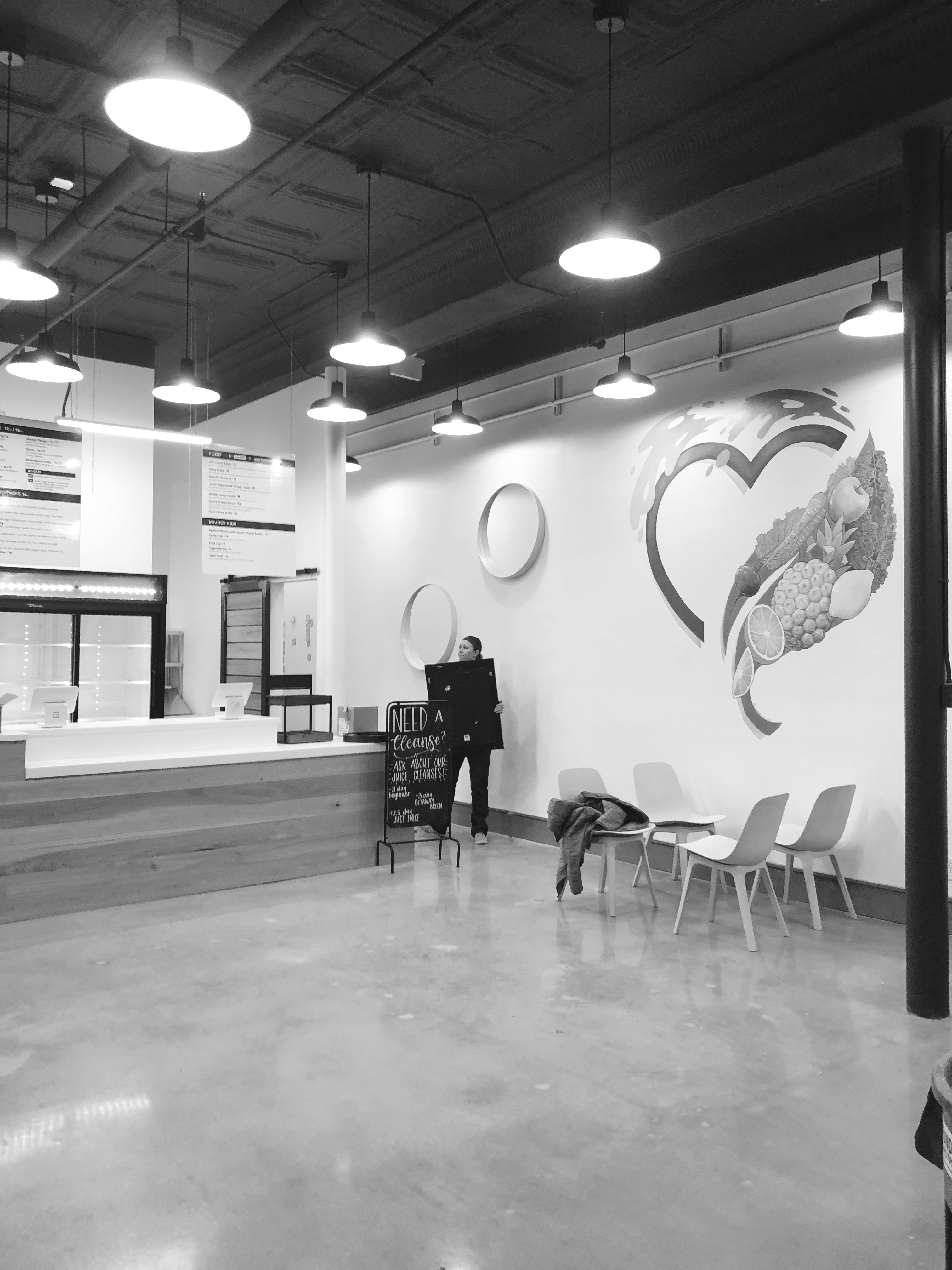 woman standing in a large open café holding a picture frame