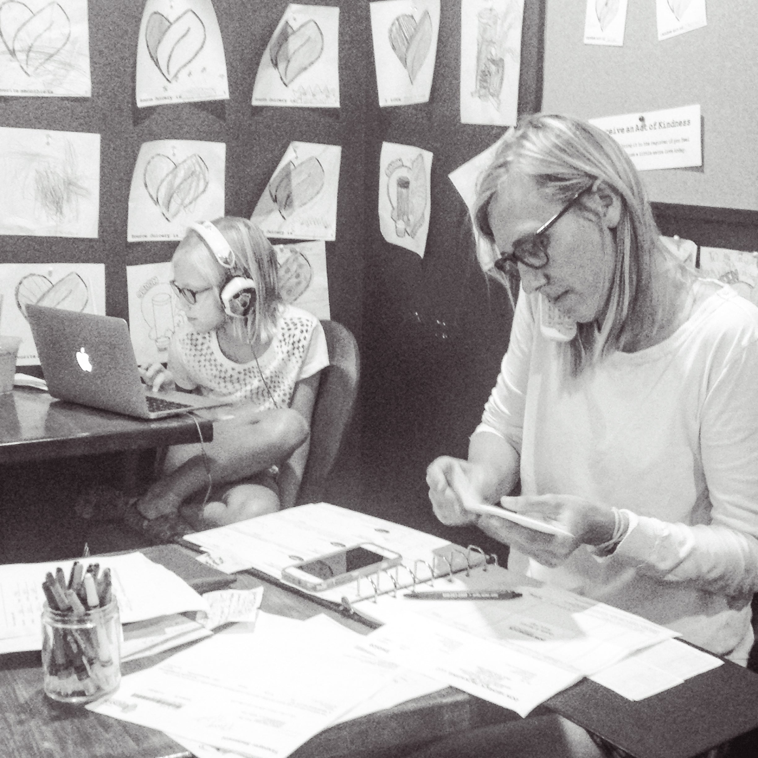 a mom and her daighter sitting in an office working and on the phone in black and white