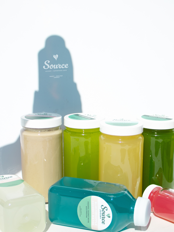 a group glass jars filled with juice and a logo on a shaodow in the background against a white backdrop