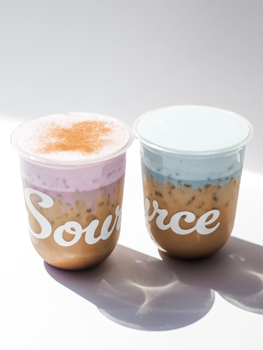 Two lattes with purple and blue cold foam against a white backdrop with shadows