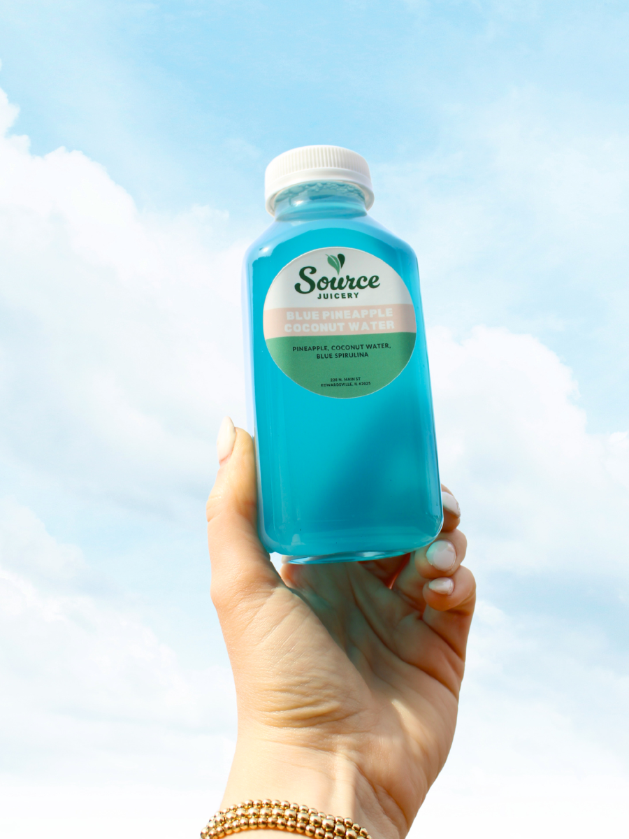bottle of blue coconut water being held against a sky background